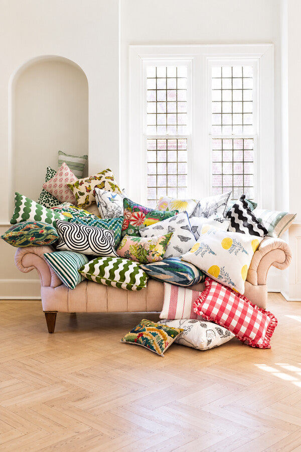 Schumacher decorative pillows layered on a sofa with contrasting patterns and sizes