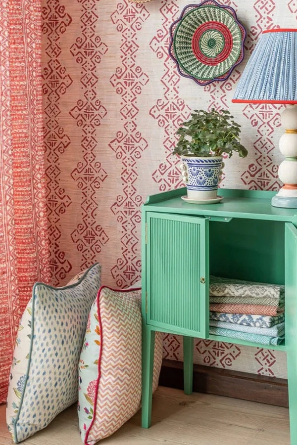 1. Blithfield fabric and wallpaper interior with coral patterned drapery, decorative pillows and colorful geometric wallcovering