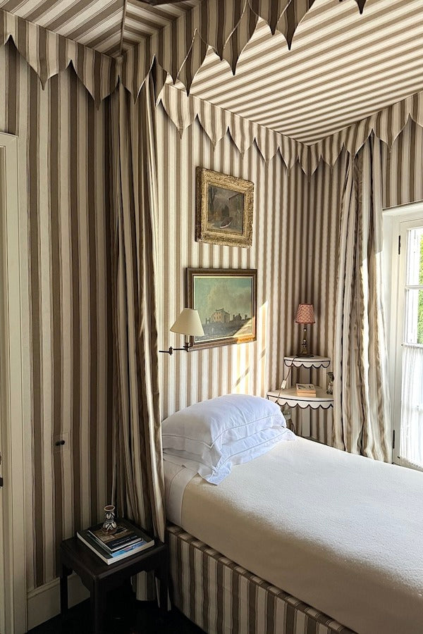 Veere Grenney guest bedroom with striped fabric walls, canopy bed and coordinating striped curtains.